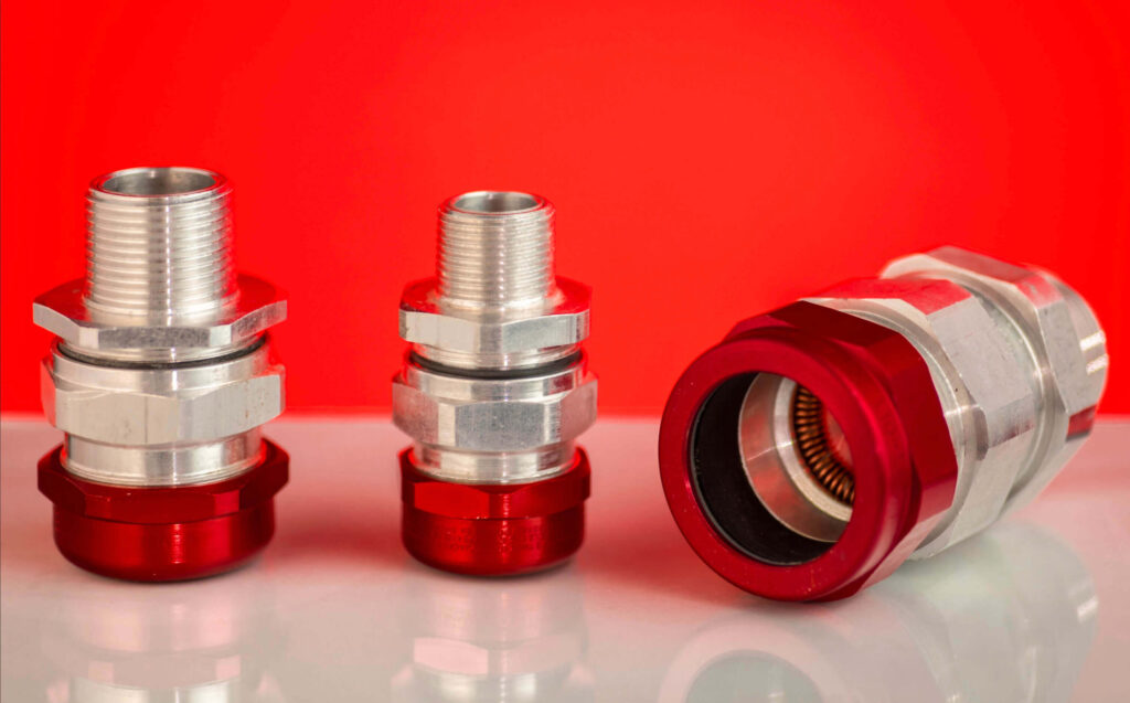 Conectores TMCX metálicos con base roja para instalaciones eléctricas industriales.